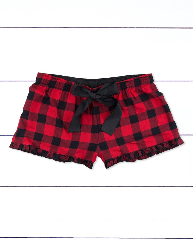 May include: Red and black plaid pajama shorts with a black bow tie at the waist. The shorts have a ruffled hem.