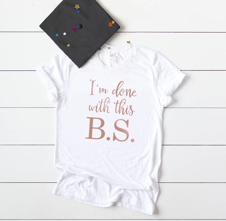 May include: White t-shirt with the text "I'm done with this B.S." in rose gold lettering.