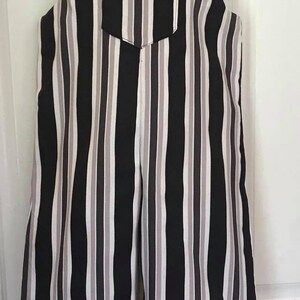 May include: Overalls with a vertical striped pattern in black, white, and gray. The overalls have a front pocket and adjustable straps with button closures. The garment is displayed on a mannequin.