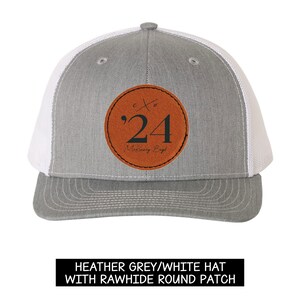 May include: Heather grey and white trucker hat with a rawhide round patch. The patch features the number '24' and the name 'McKinney Boyd' in a circular design. The hat has a mesh back and a curved brim.