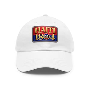 May include: White baseball cap featuring a rectangular patch with the text "HAITI 1804" in gold lettering. The patch has a red and blue background with a small Haitian flag emblem.