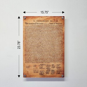 May include: A framed print of the Declaration of Independence on a white wall. The print is 15.75 inches wide and 23.78 inches tall. The print is on a parchment-like background with brown text and signatures.