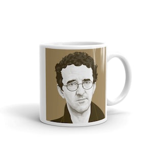 Pode incluir: Caneca de cerâmica branca com um retrato de um homem com óculos e cabelo encaracolado. O retrato é em tons de castanho e preto. A caneca tem uma pega branca e um fundo branco liso.