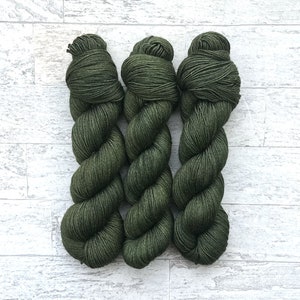 May include: Three skeins of dark green yarn, twisted and arranged in a vertical row.
