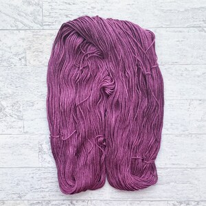 May include: A skein of deep purple yarn, a soft and fluffy texture, ready for knitting or crocheting.