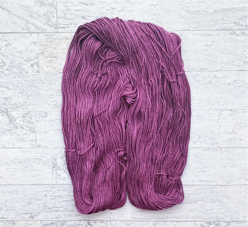 May include: A skein of deep purple yarn, a soft and fluffy texture, ready for knitting or crocheting.