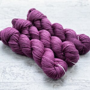 May include: Three skeins of purple yarn, twisted together, ready for knitting or crocheting.