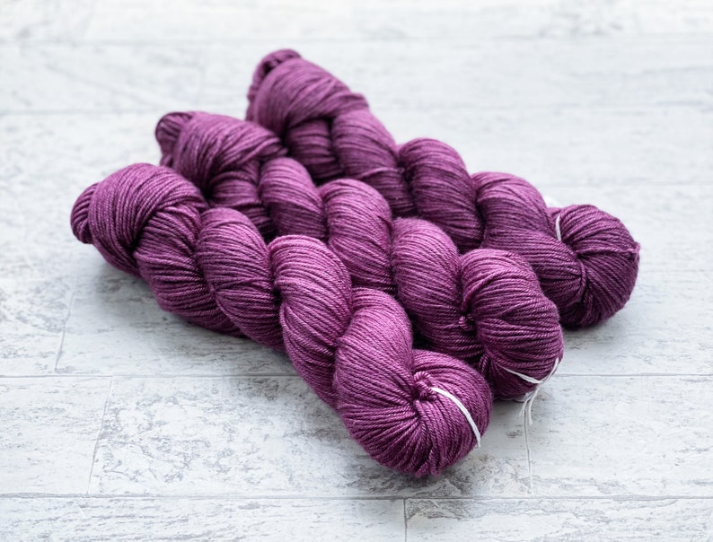 May include: Three skeins of purple yarn, twisted together, ready for knitting or crocheting.