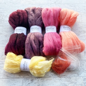 May include: Five skeins of wool roving in shades of burgundy, purple, pink, orange, and yellow. The skeins are labelled "Banshee Fiber Art Studio".
