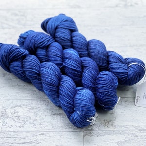 May include: Three skeins of deep blue yarn, with a white tag that reads "74027" and "20% Cashmere Wool 80% Superwash Merino 437 yards / 400 metres 100 grams / 3.5 oz.  Crafted in Canada."