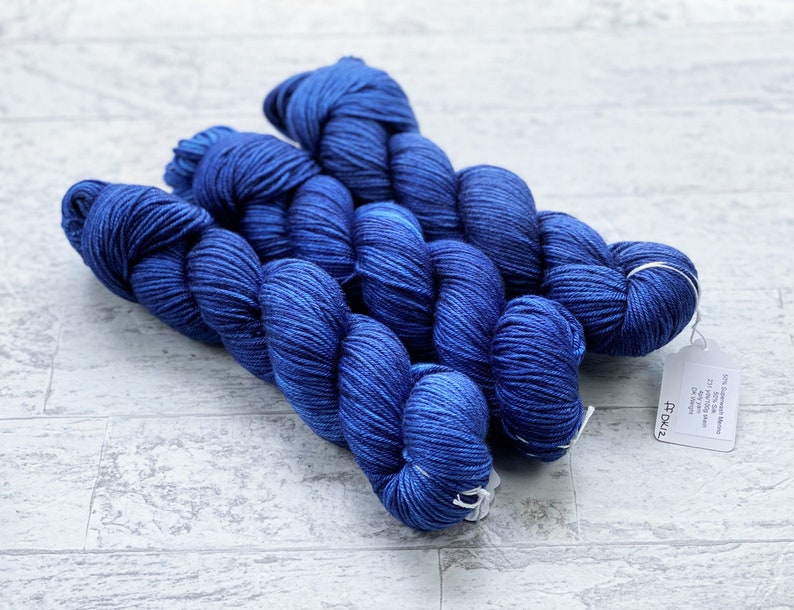 May include: Three skeins of deep blue yarn, with a white tag that reads "74027" and "20% Cashmere Wool 80% Superwash Merino 437 yards / 400 metres 100 grams / 3.5 oz.  Crafted in Canada."