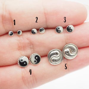 May include: Five pairs of yin yang earrings in different sizes and styles. The earrings are silver with black and white yin yang symbols. The earrings are numbered 1 through 5.