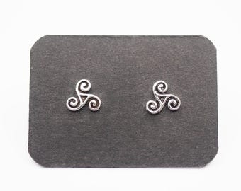 May include: A pair of silver stud earrings featuring a Celtic triskelion design. The earrings are displayed on a black card.