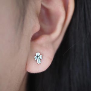 K&ouml;nnte beinhalten: Ein Paar silberne Ohrstecker in Form eines Engels. Die Ohrringe sind klein und zart und w&auml;ren ein tolles Geschenk f&uuml;r einen besonderen Menschen.