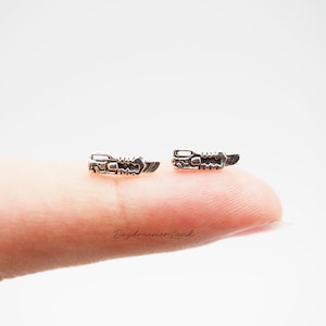 Może przedstawiać: Para srebrnych kolczyków w kształcie małego ostrza piły.