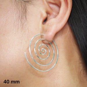 Peut inclure: Boucles d'oreilles créoles en argent en forme de spirale, de 40 mm de diamètre. Les boucles d'oreilles sont faites d'un seul fil continu qui est torsadé en forme de spirale.