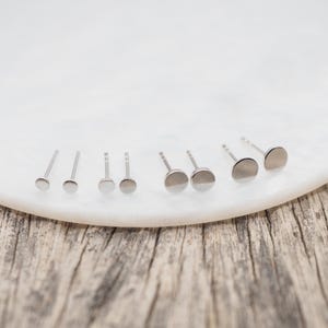 May include: A set of six silver stud earrings of varying sizes, displayed on a white surface.