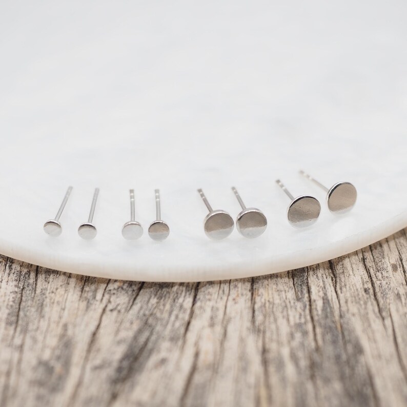 May include: A set of six silver stud earrings of varying sizes, displayed on a white surface.