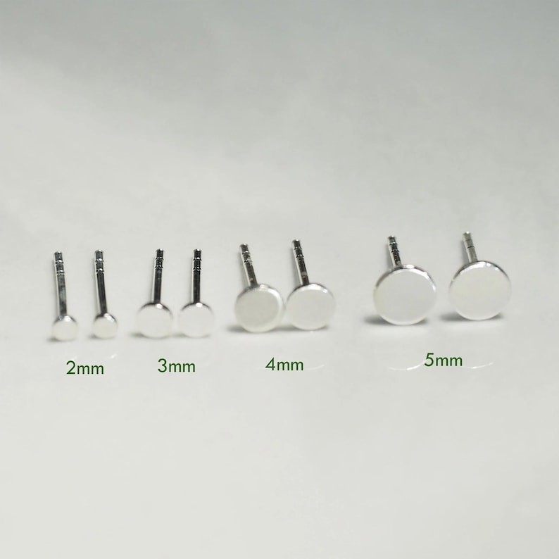 May include: A set of six pairs of silver stud earrings in various sizes, ranging from 2mm to 5mm. The earrings are displayed on a white surface.