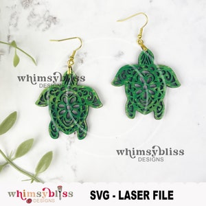 May include: A pair of green wooden turtle earrings with intricate cutouts. The earrings are on a white background with the text "whimsybless DESIGNS" and "SVG - LASER FILE" visible.