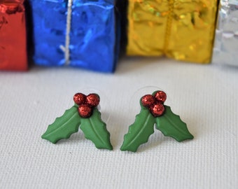 May include: A pair of green holly leaf earrings with red glitter berries.
