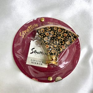 ヴィンテージのストラットン製ファン型リップスティックミラー、黒と金の花柄デザイン、小売用パッケージ入り