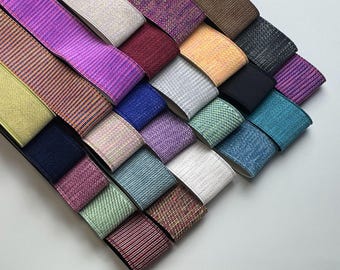 Può includere: Assortimento di elastici colorati con diversi motivi e trame. Gli elastici sono disposti a ventaglio, con le estremità di ogni elastico che si sovrappongono.