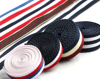 May include: Four different types of striped ribbon, including red, white, blue, and black. The ribbons are rolled up and arranged in a semi-circle.