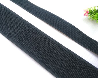 May include: Black hook and loop tape, also known as Velcro, is shown in two strips. The tape is soft and flexible, and has a textured surface.