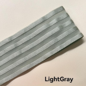Peut inclure: Une bande de tissu &eacute;lastique gris clair pr&eacute;sentant une s&eacute;rie de rayures diagonales en relief parall&egrave;les sur sa surface. Le mat&eacute;riau a une texture lisse et l&eacute;g&egrave;rement r&eacute;fl&eacute;chissante, avec le texte LightGray inscrit en bas &agrave; droite.