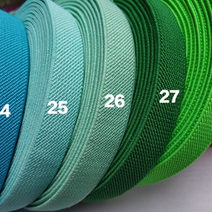 May include: Five rolls of elastic fabric in different shades of blue and green. The rolls are labeled with the numbers 24, 25, 26, 27, and 28.