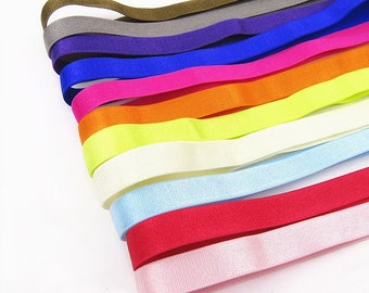May include: A collection of colorful elastic headbands in various shades, including pink, orange, yellow, blue, and green. The headbands are neatly arranged, showcasing their vibrant hues and textures. The image is taken against a white background, highlighting the headbands.