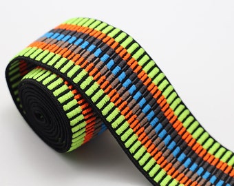Può includere: Nastro elastico nero con strisce colorate in verde, arancione, blu e marrone. Le strisce sono realizzate in tessuto testurizzato.