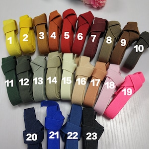 May include: Twenty-three different colors of elastic webbing, each with a number from 1 to 23. The webbing is folded in half and tied in a knot.
