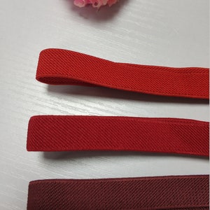 May include: Three different colors of elastic fabric, from top to bottom: red, red, and burgundy. The fabric is textured and has a slight sheen.