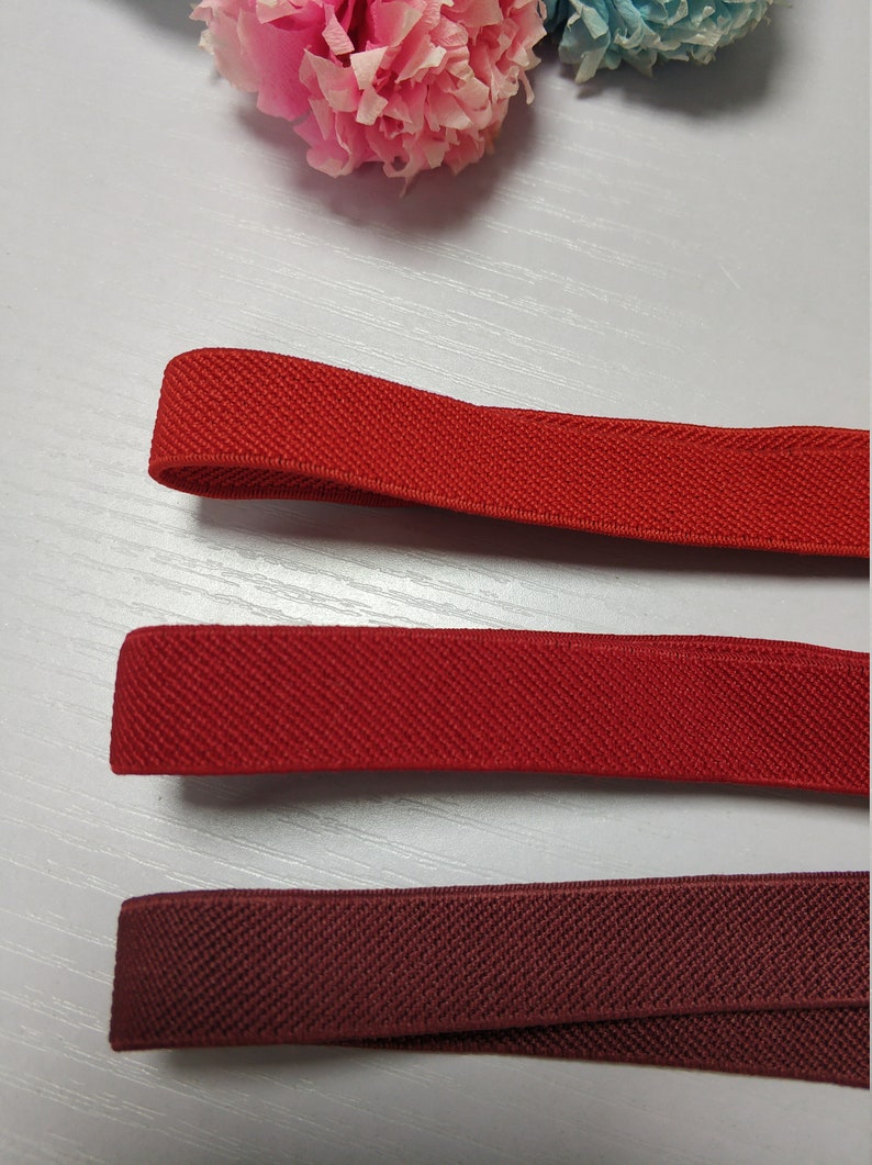 May include: Three different colors of elastic fabric, from top to bottom: red, red, and burgundy. The fabric is textured and has a slight sheen.