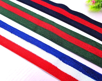 May include: Three different types of elastic trim with striped patterns. The first trim is green and red, the second is navy blue and red, and the third is red, white, and blue.