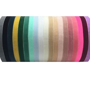 May include: A collection of 18 velvet ribbon spools in various colors, including gray, black, yellow, green, light blue, white, beige, pink, fuchsia, and purple.