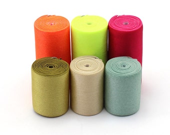 Puede incluir: Seis rollos de tejido elástico en diferentes colores: naranja, verde lima, rojo, verde oliva, beige y azul claro.