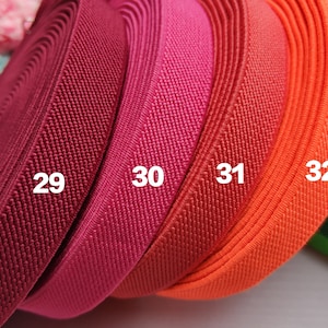 May include: Four rolls of elastic fabric in different colors: burgundy, pink, red, and orange. The fabric is textured and has a ribbed pattern. The rolls are labeled with numbers 29, 30, 31, and 32.