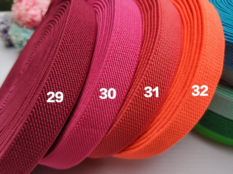 May include: Four rolls of elastic fabric in different colors: burgundy, pink, red, and orange. The fabric is textured and has a ribbed pattern. The rolls are labeled with numbers 29, 30, 31, and 32.