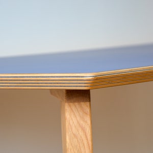 May include: Close-up of a light blue table top with a wood grain edge. The table has wooden legs.