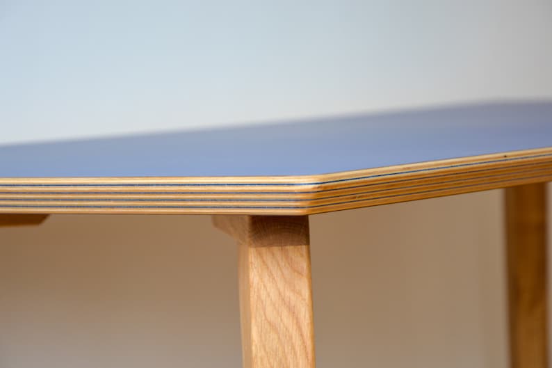 May include: Close-up of a light blue table top with a wood grain edge. The table has wooden legs.