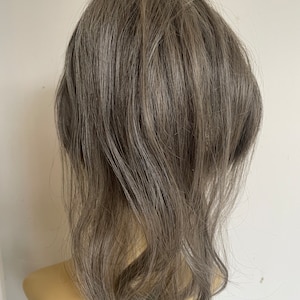 Könnte beinhalten: Eine graue Haarverlängerung mit welliger Textur. Die Haarverlängerung ist in einem gestuften Bob gestylt.