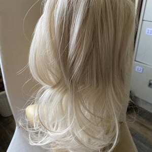May include: A long, white blonde hair extension for adding volume and length to a ponytail.