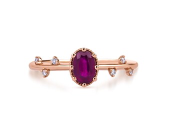 May include: A delicate rose gold ring with a vibrant ruby gemstone set in a crown-like design. The ring is adorned with small diamonds on each side of the ruby.