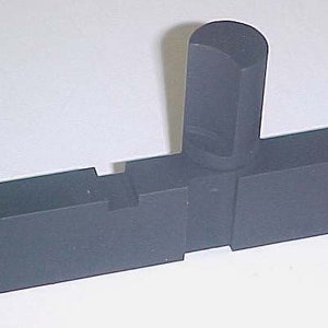 Könnte beinhalten: Ein schwarzes Werkzeug aus Metall mit einem T-förmigen Griff und einer rechteckigen Basis. Das Werkzeug hat eine kleine Kerbe an der Seite der Basis.