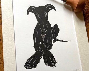 Op de afbeelding: Zwart-witte linosnede van een hond die met gekruiste poten zit. De hond heeft een hartvorm op zijn borst en de print is getiteld "Patience" en gesigneerd "M.C.B 2021".