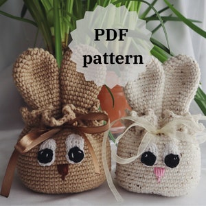 Peut inclure: Deux sacs en crochet en forme de lapin en fil brun et blanc. Les sacs ont des visages avec des yeux noirs et un nez brun. Les sacs sont attachés avec un ruban et sont prêts pour Pâques.