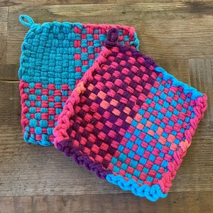 May include: Two woven pot holders, one blue and pink, the other pink and blue, with a checkered pattern.